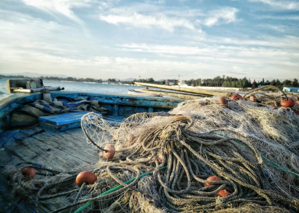pexels-photo-891118-891118 Rustic fishing boat with nets in Hammamet, Tunisia on a serene day.